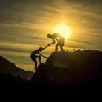 Una persona ayudando a subir una montaña a otra persona